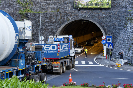 Estreito da Calheta Madeira Portugal 20 September 2026 View of a large LASO transport truck parked near the entrance of a stone tunnel with a traffic controller and cars passing through. Estreito da Calheta Madeira Portugal 20 September 2026 View of a large LASO transport truck parked near the entrance of a stone tunnel with a traffic controller and cars passing through.