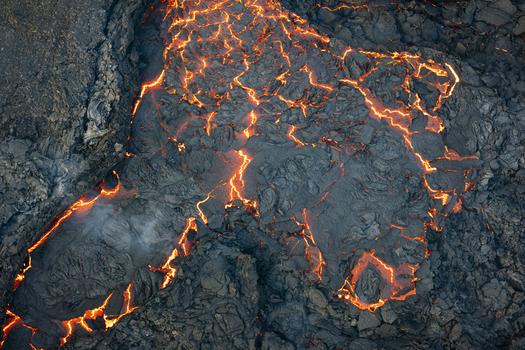 Aerial view of fiery rivers of molten lava snake through the rugged dark landscape a stark contrast of heat and stone Reykjavik Reykjanes Iceland.
