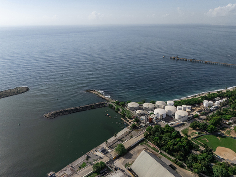 Aerial view of the industrial area of Haina featuring large storage tanks a pier and a breakwater along the coastline in Bajos de Haina San Cristobal Province Dominican Republic.