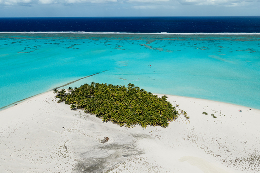 Aerial view of Aitutaki featuring a small tropical island with lush palm trees surrounded by white sand beaches and a vibrant turquoise lagoon in the Cook Islands. Aerial view of Aitutaki featuring a small tropical island with lush palm trees surrounded by white sand beaches and a vibrant turquoise lagoon in the Cook Islands.