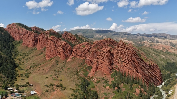 Aerial view of the iconic red sandstone rock formations of Jety Oguz with lush green slopes pine forests and a winding river Jety Oguz Issyk Kul Region Kyrgyzstan. Aerial view of the iconic red sandstone rock formations of Jety Oguz with lush green slopes pine forests and a winding river Jety Oguz Issyk Kul Region Kyrgyzstan.