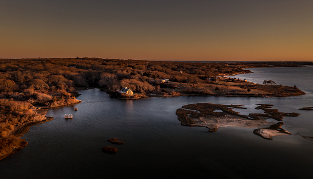 View of Martha s Vineyard coastal landscape with a white house bare trees and calm waters at sunset Edgartown Massachusetts United States.