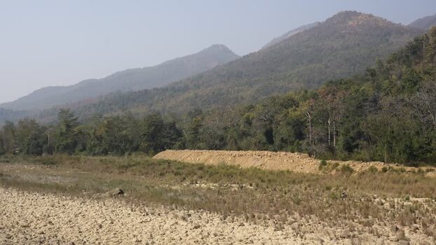 View of a dry riverbed and forested hills Nepal.