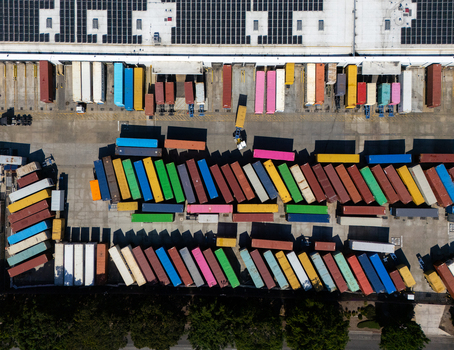 Aerial view of a busy shipping container yard with rows of colorful containers arranged in an industrial facility in Carson California United States.