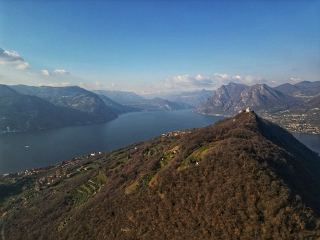 Aerial view of Monte Isola island ridge overlooking Lake Iseo with surrounding mountains and clear blue sky Monte Isola Lombardy Italy. Aerial view of Monte Isola island ridge overlooking Lake Iseo with surrounding mountains and clear blue sky Monte Isola Lombardy Italy.