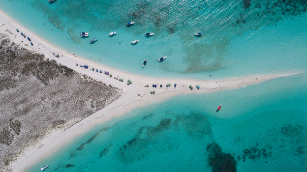 Aerial view of Los Roques archipelago featuring a white sandbar in turquoise waters with anchored boats and beach umbrellas in Los Roques Dependencias Federales Venezuela. Aerial view of Los Roques archipelago featuring a white sandbar in turquoise waters with anchored boats and beach umbrellas in Los Roques Dependencias Federales Venezuela.