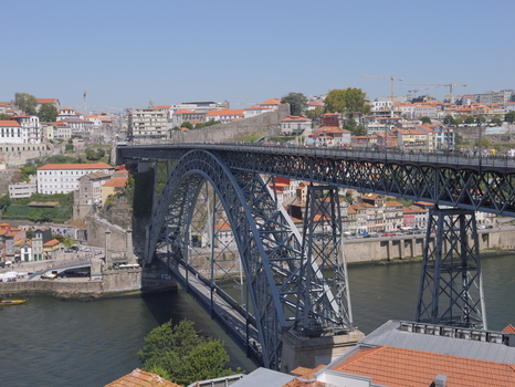 View of the iconic Dom Luis I Bridge spanning the Douro River with historic buildings and terracotta rooftops in the background in Porto Porto District Portugal. View of the iconic Dom Luis I Bridge spanning the Douro River with historic buildings and terracotta rooftops in the background in Porto Porto District Portugal.