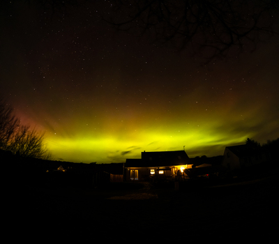 Aerial view of the Aurora Borealis illuminating the night sky above a residential house in the countryside Portnoo County Donegal Ireland. Aerial view of the Aurora Borealis illuminating the night sky above a residential house in the countryside Portnoo County Donegal Ireland.