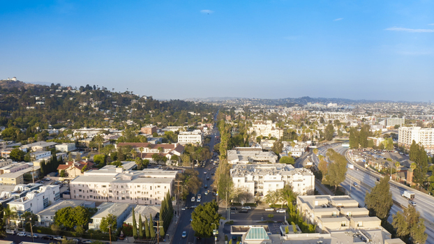 Aerial view of the urban landscape of Los Angeles with residential buildings palm trees and a highway stretching through the city in Los Angeles California United States.