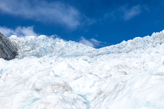 View of a dazzling icy glacier cascading under a brilliant blue sky an untouched landscape of pure frozen wonder Franz Josef Glacier West Coast Region New Zealand. View of a dazzling icy glacier cascading under a brilliant blue sky an untouched landscape of pure frozen wonder Franz Josef Glacier West Coast Region New Zealand.