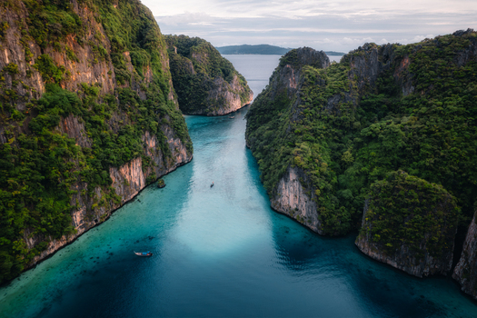 Aerial view of Pi Leh Bay featuring limestone cliffs lush vegetation and clear turquoise water with traditional long tail boats in Tambon Ao Nang Chang Wat Krabi Thailand. Aerial view of Pi Leh Bay featuring limestone cliffs lush vegetation and clear turquoise water with traditional long tail boats in Tambon Ao Nang Chang Wat Krabi Thailand.