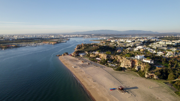 Aerial view of the coastal town of Ferragudo featuring sandy beaches rocky cliffs and the Arade River estuary in Ferragudo Faro District Portugal.