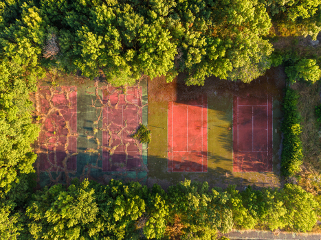Aerial view of abandoned tennis courts with cracked red clay surfaces surrounded by dense green forest in Kiten Burgas Bulgaria. Aerial view of abandoned tennis courts with cracked red clay surfaces surrounded by dense green forest in Kiten Burgas Bulgaria.