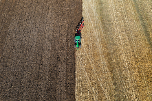 Aerial view of a vibrant green tractor contrasting against the dark earth and golden stubble in a freshly plowed field Chyhyryns kyi district Cherkasy Oblast Ukraine. Aerial view of a vibrant green tractor contrasting against the dark earth and golden stubble in a freshly plowed field Chyhyryns kyi district Cherkasy Oblast Ukraine.