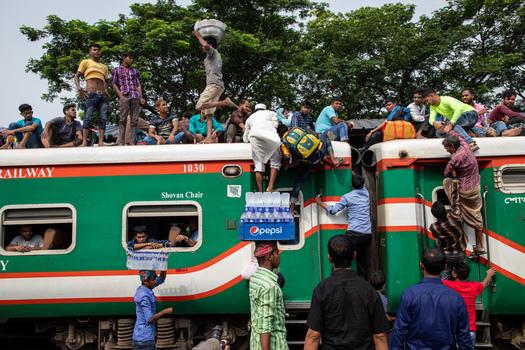 Dhaka Bangladesh 14 June 2018 View of people crowded on the roof and sides of a train at Airport Railway Station with a vendor carrying water bottles. Dhaka Bangladesh 14 June 2018 View of people crowded on the roof and sides of a train at Airport Railway Station with a vendor carrying water bottles.