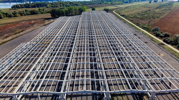 Aerial view of the large concrete hall structure under construction featuring a vast grid of beams and columns set against a rural landscape in Kovin Vojvodina Serbia. Aerial view of the large concrete hall structure under construction featuring a vast grid of beams and columns set against a rural landscape in Kovin Vojvodina Serbia.