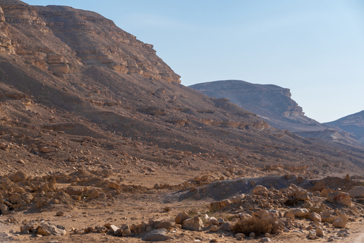 View of arid rocky terrain under a clear sky with layered cliffs and desert vegetation creating a stark sun drenched landscape Cairo Egypt. View of arid rocky terrain under a clear sky with layered cliffs and desert vegetation creating a stark sun drenched landscape Cairo Egypt.