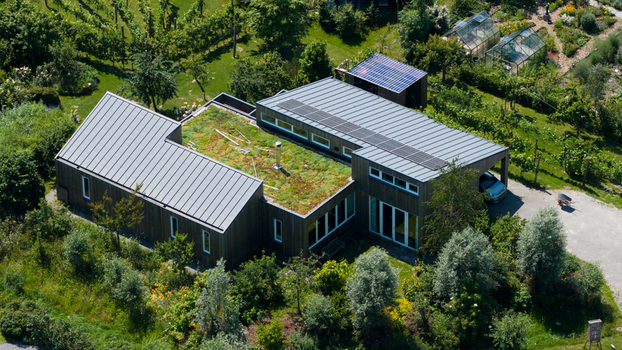 Aerial view of Ecodorp Bolderburen a modern house with a green sedum roof and solar panels surrounded by lush gardens trees and greenhouses in Almere Flevoland Netherlands. Aerial view of Ecodorp Bolderburen a modern house with a green sedum roof and solar panels surrounded by lush gardens trees and greenhouses in Almere Flevoland Netherlands.