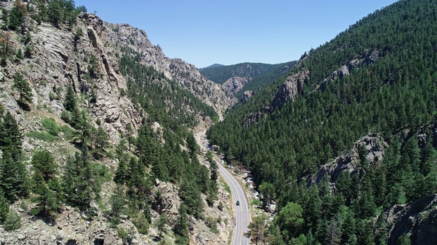 Aerial view of the winding road near Bihedral Trail Head surrounded by steep rocky canyon walls and dense pine forests in Nederland Colorado United States. Aerial view of the winding road near Bihedral Trail Head surrounded by steep rocky canyon walls and dense pine forests in Nederland Colorado United States.