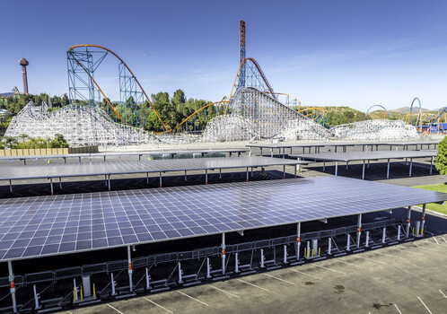 Valencia CA United States 08 April 2026 Aerial view of solar panel canopies over a parking lot at Six Flags Magic Mountain with a roller coaster in the background under a clear sky. Valencia CA United States 08 April 2026 Aerial view of solar panel canopies over a parking lot at Six Flags Magic Mountain with a roller coaster in the background under a clear sky.