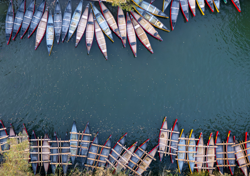 Aerial view of vibrant canoes lining the serene waters edge their colorful hulls a stark contrast to the deep blue Kineret Israel.