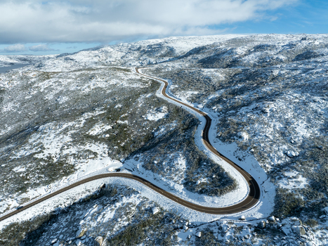 Aerial view of a winding road slicing through a snow dusted landscape contrasting dark asphalt with the pristine white of the winter terrain São Romão Guarda District Portugal. Aerial view of a winding road slicing through a snow dusted landscape contrasting dark asphalt with the pristine white of the winter terrain São Romão Guarda District Portugal.