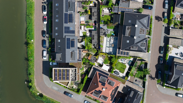 Aerial view of modern residential houses with dark roofs solar panels and green gardens situated along a canal in Utrecht Utrecht Netherlands. Aerial view of modern residential houses with dark roofs solar panels and green gardens situated along a canal in Utrecht Utrecht Netherlands.