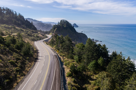 Aerial view of the winding Highway 101 along the rugged coastline with dense evergreen forests and the Pacific Ocean Port Orford Oregon United States. Aerial view of the winding Highway 101 along the rugged coastline with dense evergreen forests and the Pacific Ocean Port Orford Oregon United States.