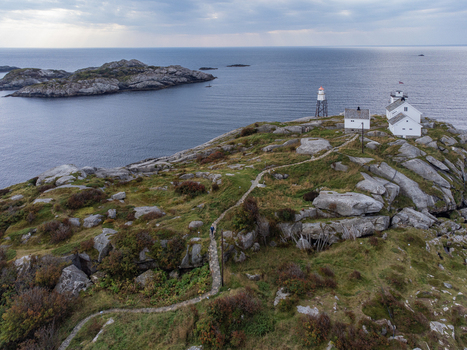 Aerial view of stark white buildings contrast against the rugged moss covered landscape under a brooding sky Henningsvær Nordland Norway. Aerial view of stark white buildings contrast against the rugged moss covered landscape under a brooding sky Henningsvær Nordland Norway.