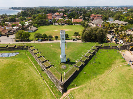 Aerial view of the Matara Fort Clock Tower standing on historic stone ramparts surrounded by green lawns and the urban landscape Matara Southern Province Sri Lanka. Aerial view of the Matara Fort Clock Tower standing on historic stone ramparts surrounded by green lawns and the urban landscape Matara Southern Province Sri Lanka.