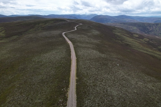 Aerial view of a winding dirt road traversing the grassy ridge of Mount Morrone under a cloudy sky in Mount Morrone Scotland United Kingdom. Aerial view of a winding dirt road traversing the grassy ridge of Mount Morrone under a cloudy sky in Mount Morrone Scotland United Kingdom.