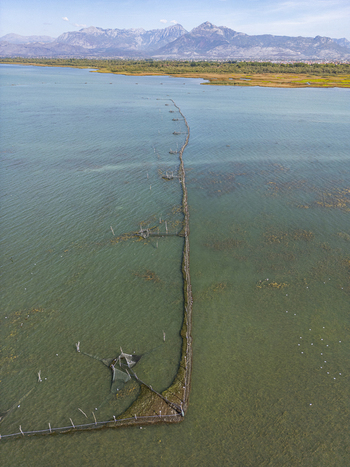 Aerial view of traditional fishing structures in Shkodra Lake with mountains in the background in Shiroka Shkoder County Albania. Aerial view of traditional fishing structures in Shkodra Lake with mountains in the background in Shiroka Shkoder County Albania.