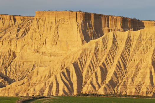 View of the dramatic eroded sandstone cliffs and plateaus of Bardenas Reales under warm golden light Navarre Navarre Spain. View of the dramatic eroded sandstone cliffs and plateaus of Bardenas Reales under warm golden light Navarre Navarre Spain.