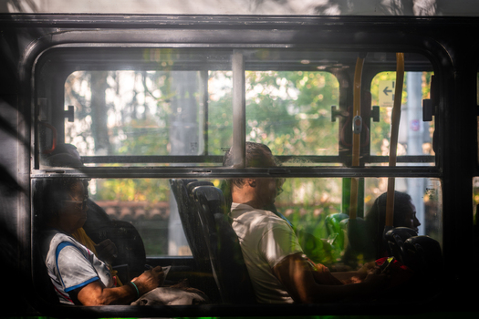 Rio de Janeiro Brazil 09 June 2026 View of passengers sitting inside a public bus with sunlight filtering through the windows and lush green trees visible in the background.