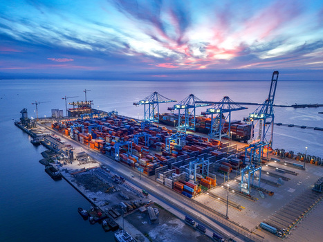 Aerial view of the Vado Ligure container port with rows of colorful shipping containers towering cranes and automated infrastructure along the coast at dusk in Vado Ligure Liguria Italy. Aerial view of the Vado Ligure container port with rows of colorful shipping containers towering cranes and automated infrastructure along the coast at dusk in Vado Ligure Liguria Italy.