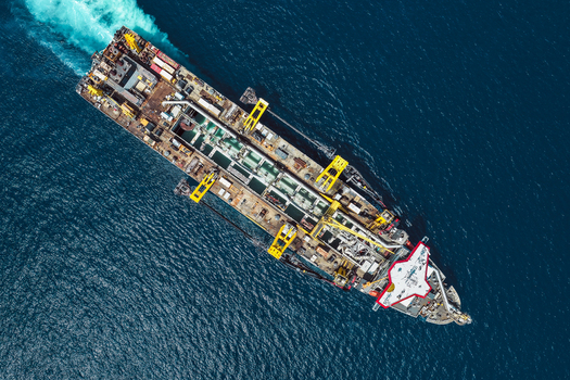 Aerial view of a large dredger vessel with yellow cranes navigating through deep blue ocean waters leaving a white wake Vashafaru Haa Alif Atoll Maldives. Aerial view of a large dredger vessel with yellow cranes navigating through deep blue ocean waters leaving a white wake Vashafaru Haa Alif Atoll Maldives.