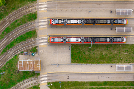 Aerial view of modern trams parked at a depot with parallel tracks paved platforms and surrounding green spaces in Warsaw Mazowieckie Poland. Aerial view of modern trams parked at a depot with parallel tracks paved platforms and surrounding green spaces in Warsaw Mazowieckie Poland.