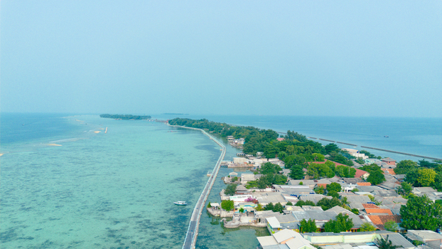 Aerial view of Tidung Island featuring a long bridge connecting the land to the sea surrounded by turquoise waters and lush tropical vegetation in South Kepulauan Seribu Jakarta Indonesia.