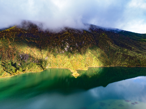Aerial view of Lagoa do Fogo crater lake surrounded by steep green volcanic slopes and misty mountain peaks under a cloudy sky Agua de Alto Azores Portugal. Aerial view of Lagoa do Fogo crater lake surrounded by steep green volcanic slopes and misty mountain peaks under a cloudy sky Agua de Alto Azores Portugal.
