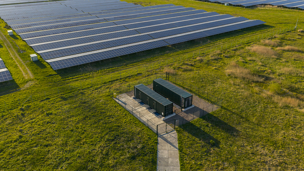 Aerial view of rows of solar panels and battery storage containers in a green field under warm sunlight Farmsum Groningen Netherlands. Aerial view of rows of solar panels and battery storage containers in a green field under warm sunlight Farmsum Groningen Netherlands.