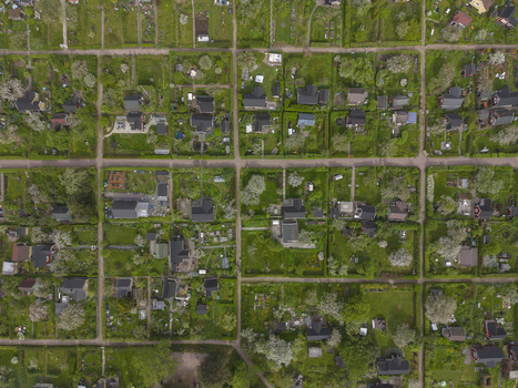 Aerial view of a residential neighborhood with grid patterned streets houses and lush green gardens in Helsinki Uusimaa Finland.