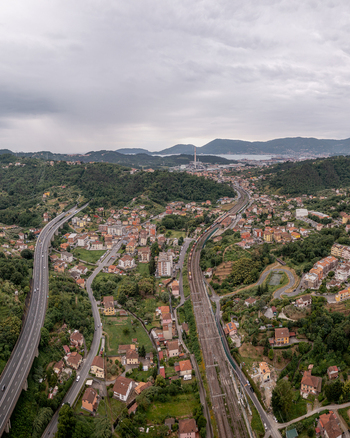 Aerial view of the town of Vezzano Ligure with its railway tracks highway viaduct and surrounding green hills under a cloudy sky in Vezzano Ligure Liguria Italy.
