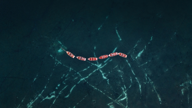 Aerial view of wooden rowing boats floating in a line on the turquoise water Braies Trentino Alto Adige Italy. Aerial view of wooden rowing boats floating in a line on the turquoise water Braies Trentino Alto Adige Italy.