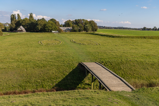 View of the Viking Fortress Trelleborg with its reconstructed wooden bridge grassy ramparts and ancient house foundations in Slagelse Sjaelland Denmark. View of the Viking Fortress Trelleborg with its reconstructed wooden bridge grassy ramparts and ancient house foundations in Slagelse Sjaelland Denmark.