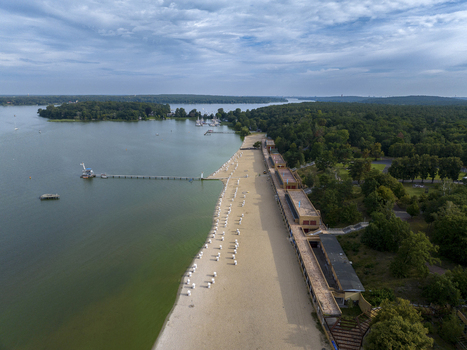 Aerial view of strandbad wannsee public beach with sandy shoreline and tranquil lake surrounded by trees Nikolassee Germany.