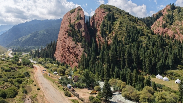 Aerial view of the Jety Oguz red sandstone rock formation surrounded by dense coniferous forests a winding road and traditional yurts near a river in Jety Oguz Issyk Kul Region Kyrgyzstan. Aerial view of the Jety Oguz red sandstone rock formation surrounded by dense coniferous forests a winding road and traditional yurts near a river in Jety Oguz Issyk Kul Region Kyrgyzstan.
