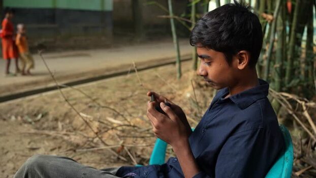 View of a boy using a smartphone in Bogura Bangladesh. View of a boy using a smartphone in Bogura Bangladesh.