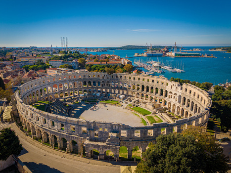 Aerial view of the magnificent Roman amphitheater stands proudly against the azure Adriatic Sea a testament to ancient grandeur Pula Istria County Croatia.