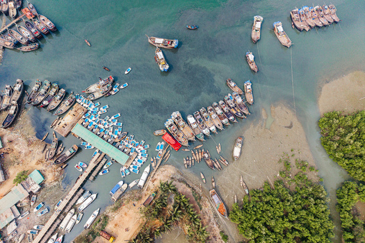 Moheskhali Upazila Bangladesh 11 March 2026 Aerial view of numerous fishing boats and speedboats docked at a jetty surrounded by turquoise water and green mangroves. Moheskhali Upazila Bangladesh 11 March 2026 Aerial view of numerous fishing boats and speedboats docked at a jetty surrounded by turquoise water and green mangroves.