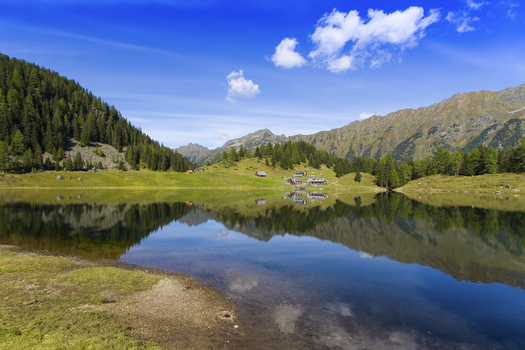 View of the serene Duisitzkarsee lake reflects the surrounding verdant alpine slopes and the clear blue sky dotted with fluffy clouds Duisitzkarsee Styria Austria. View of the serene Duisitzkarsee lake reflects the surrounding verdant alpine slopes and the clear blue sky dotted with fluffy clouds Duisitzkarsee Styria Austria.